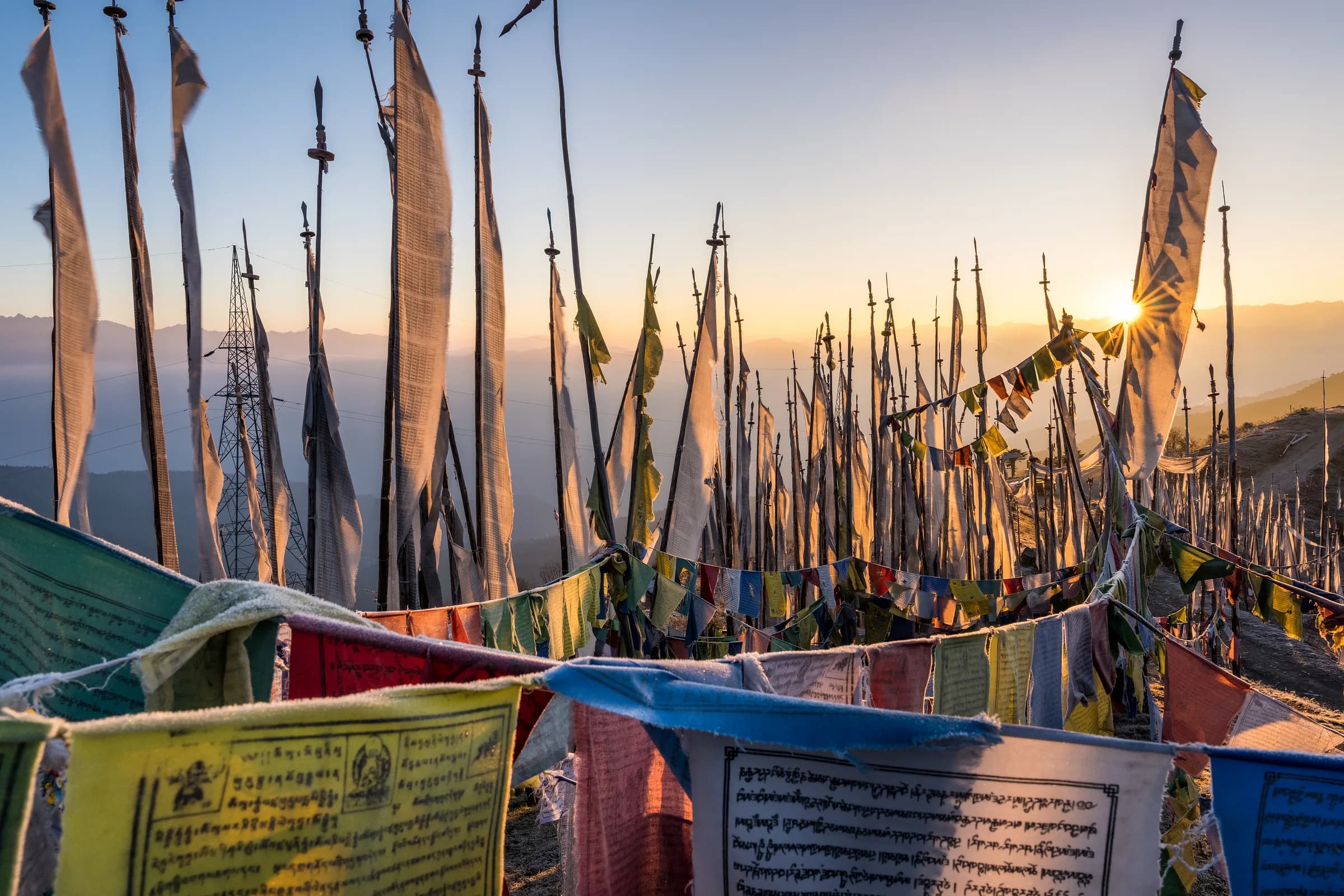 Prayer flags at sunrise above a Himalayan valley