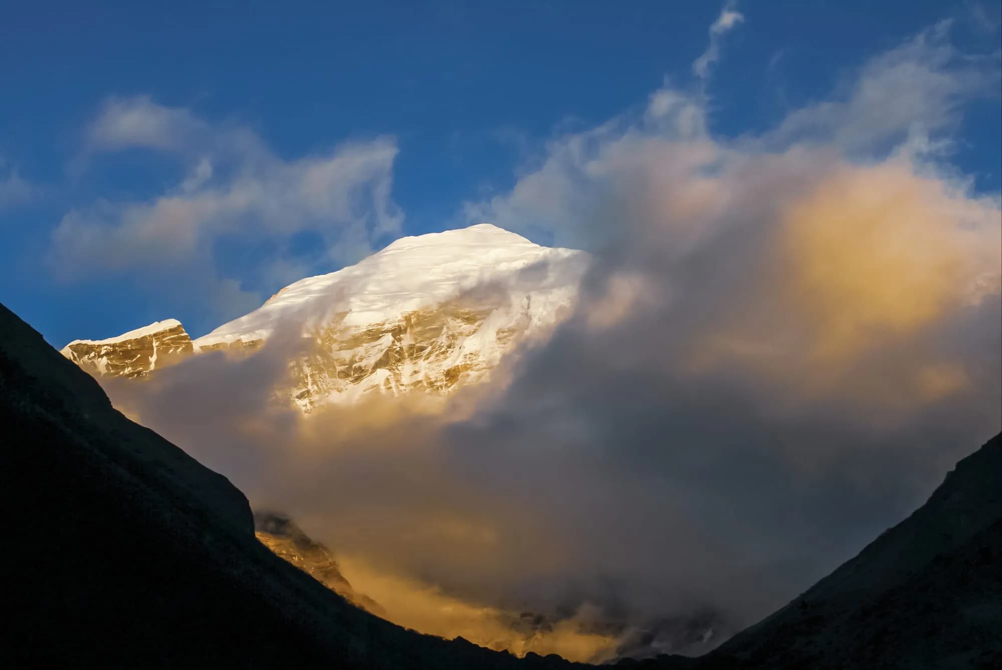 Sunlit snow peak rising above the clouds