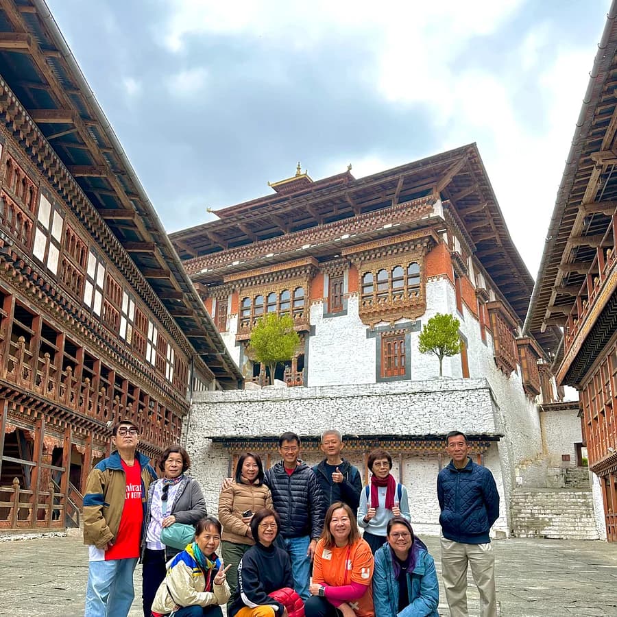 A large tour group posing in the courtyard of a Bhutanese dzong
