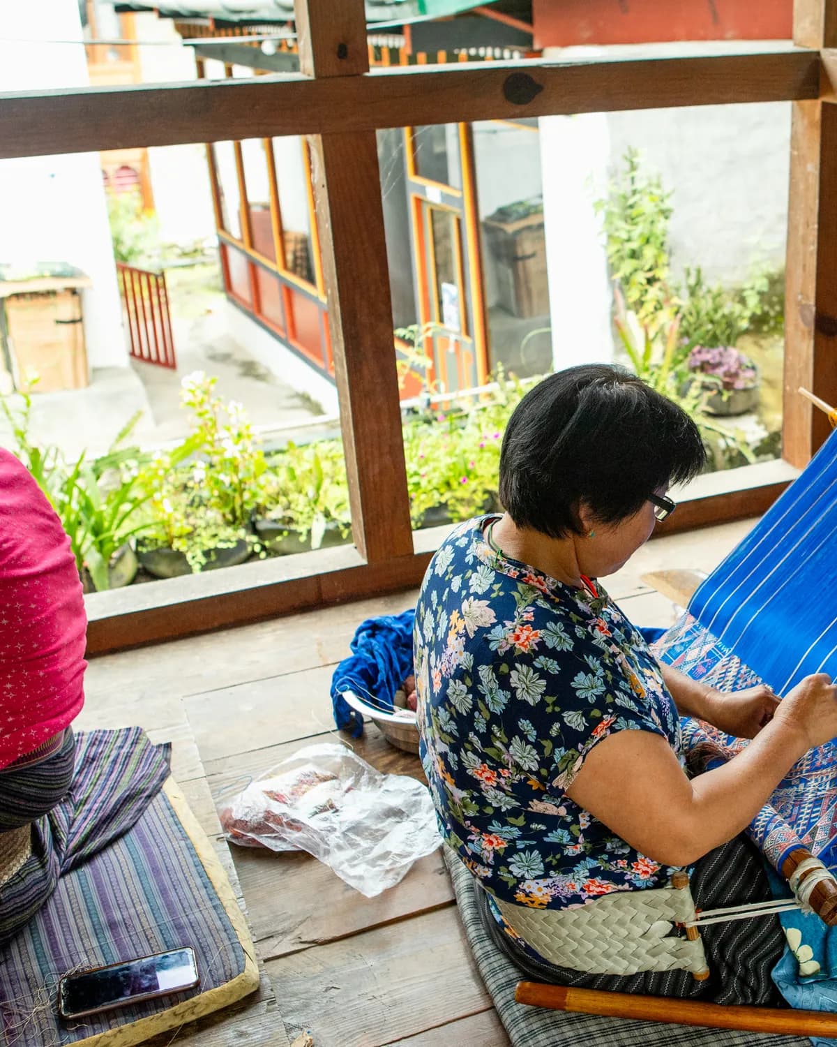 A Bhutanese woman weaving a blue silk textile on a traditional backstrap loom