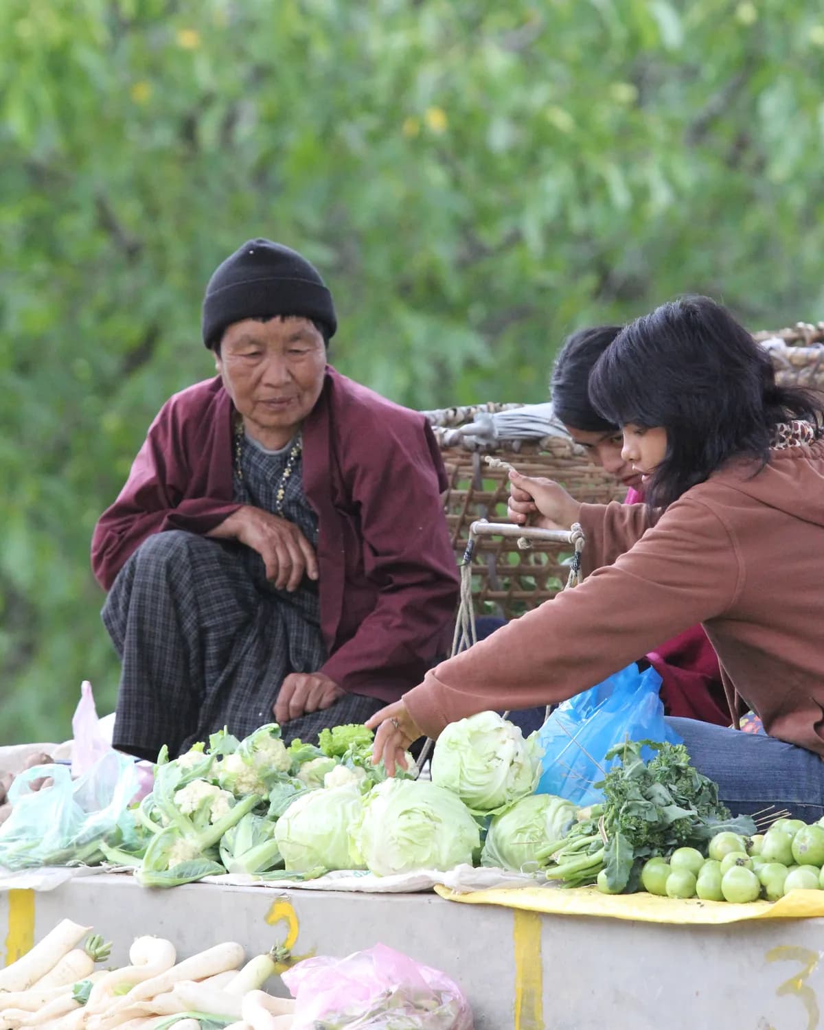 An elderly Bhutanese vendor selling fresh vegetables at a local roadside market