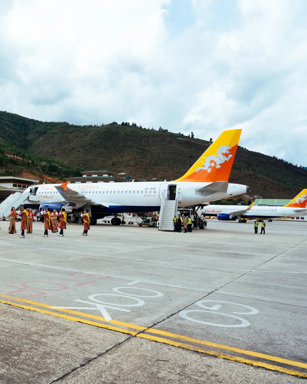 Travellers arriving on the tarmac at Paro International Airport beside a Drukair aircraft